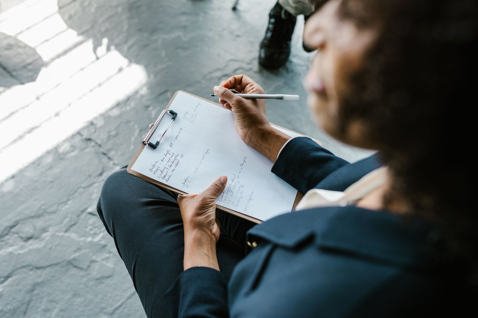Close-up of a therapist writing notes on clipboard during a counseling session.