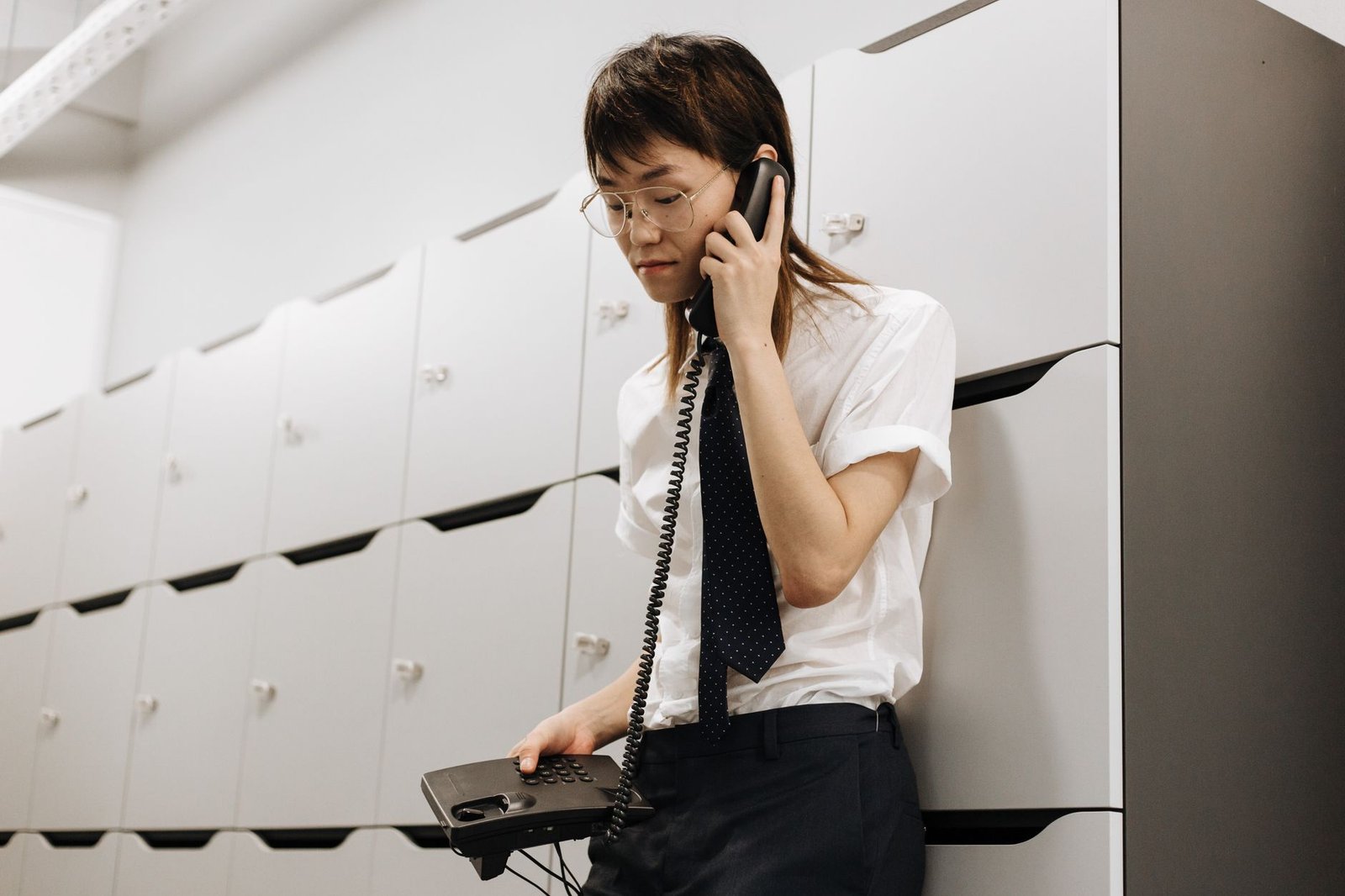 Asian male call center agent in office talking on phone, providing customer service.